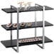 A black and silver three tier Cal-Mil metal frame riser with food on it.