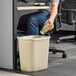 A man at a desk in a corporate office putting a paper cup into a white Lavex rectangular wastebasket.