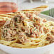 A bowl of pasta with chopped clams and toast on a plate.