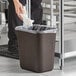 A person holding a white napkin over a brown Lavex rectangular trash can.