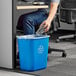 A person putting a plastic bottle into a blue Lavex recycling trash can.