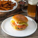 A Carlisle white melamine plate with a hamburger and fries.