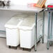 An Advance Tabco stainless steel work table with an open base holding two white plastic containers.