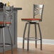A pair of Lancaster Table & Seating clear coat finish cross back swivel bar stools with cherry wood seats at a counter.
