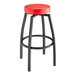 A black swivel bar stool with a red vinyl seat.