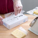 A person wearing plastic gloves wraps cheese in LK Packaging deli wrap.