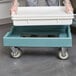 A person using a Cambro Camdolly to move a white pizza dough box.