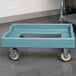 A slate blue Cambro pizza dough box dolly with wheels.