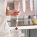 A woman using a Vollrath stainless steel long handled measuring spoon to measure red flakes.