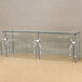 An Advance Tabco metal and glass food shield with metal posts and glass panels.