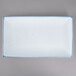 A white rectangular porcelain platter with blue speckled edges.