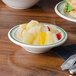 A white china bowl filled with fruit on a table.