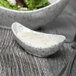 A close up of a 10 Strawberry Street Blue Speckled Porcelain Canoe Bowl with white sauce in it and a spoon.