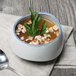 An Arctic Blue porcelain demi bowl filled with soup with a spoon.