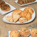 A 10 Strawberry Street Arctic Blue porcelain platter filled with pastries and muffins on a table in a bakery display.