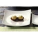 A CAC Super White square porcelain plate with sushi on it.