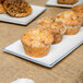 A rectangular porcelain platter holding a group of muffins.