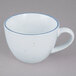 A white porcelain coffee cup with a blue rim.