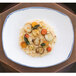 A rectangular white porcelain platter with a plate of risotto and vegetables on a table.