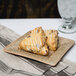 A 10 Strawberry Street Tiger Eye porcelain bread and butter plate with two scones on it on a table with a glass of water.