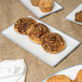 A rectangular porcelain platter with a variety of pastries on a table.