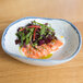 A table set with a 10 Strawberry Street Arctic Blue porcelain bowl filled with salmon, greens, and herbs.