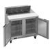 A stainless steel refrigerated sandwich prep table with two open doors, interior shelves, and ingredient bins on top.