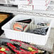 A white Metro tote box with a divider inside holding items.