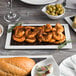A white Tuxton rectangular plate with shrimp and bread on a table.
