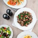 A table with Tuxton pasta bowls of food including salad, eggs, and mushrooms.