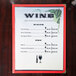 Menu paper with a grapevine and wine glass design on a table.