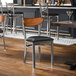 A metal chair with a black vinyl seat and an antique walnut wood backrest.