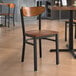 A Lancaster Table & Seating Boomerang Series chair with an antique walnut wood seat and back on a table in a restaurant.