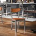 A metal chair with an antique walnut wood seat and backrest, featuring a clear coat finish.