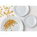 A close-up of a Tuxton TuxTrendz Sandbar bright white china plate with a plate of pasta.