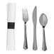 A set of stainless steel look plastic cutlery including a fork, knife, spoon, and a wrapped white linen-feel napkin.