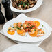 A Tuxton Charleston china oval platter with mushrooms, spinach, shrimp, and orange slices on a table.