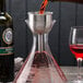 A Franmara stainless steel decanter funnel set with red wine being poured into a decanter.