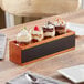 An Acopa flight crate with Barbary tasting glasses holding desserts on a wooden table.