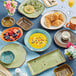 A table with white Tuxton ramekins filled with yellow soup and a bowl of fruit.