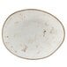 A white oval Tuxton china plate with brown specks on the rim.