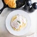 A TuxTrendz Charleston white china plate with food and a sprig of rosemary.