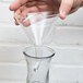 A hand using a Franmara glass decanter funnel to pour liquid into a glass.