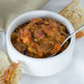A bowl of Spring Glen Fresh Foods chili with a spoon next to a piece of bread.