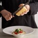 A person using a 1/4 wheel of Parmigiano Reggiano cheese to cut a plate of food.