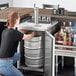 A woman opening a silver Beverage-Air beer keg dispenser.