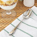 A Oneida stainless steel oval bowl spoon on a napkin next to a glass of yogurt.