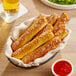 A basket of Dutch Country Foods Pennsylvania Dutch Soft Pretzel Sticks with red sauce on a table.