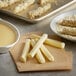 A plate of mozzarella cheese sticks with a bowl of dip on a table.