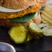 A plate of food with a Nathan's Famous sweet horseradish pickle slices sandwich and pickles.